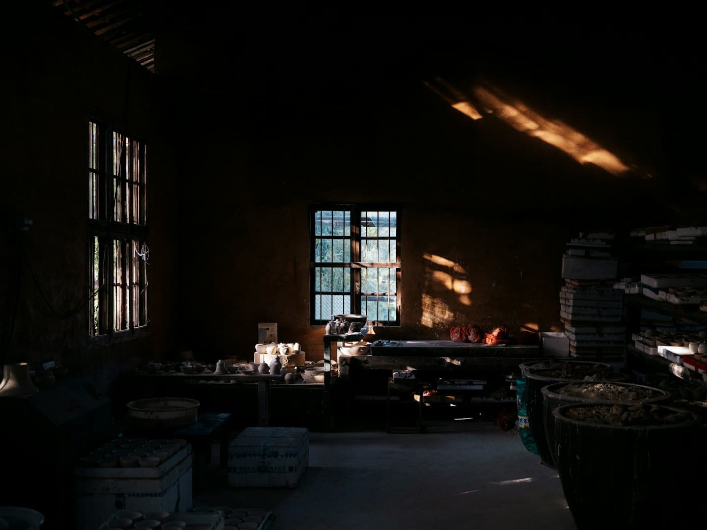 La luce del sole filtra in un laboratorio di ceramica illuminando pezzi di argilla e ceramica.