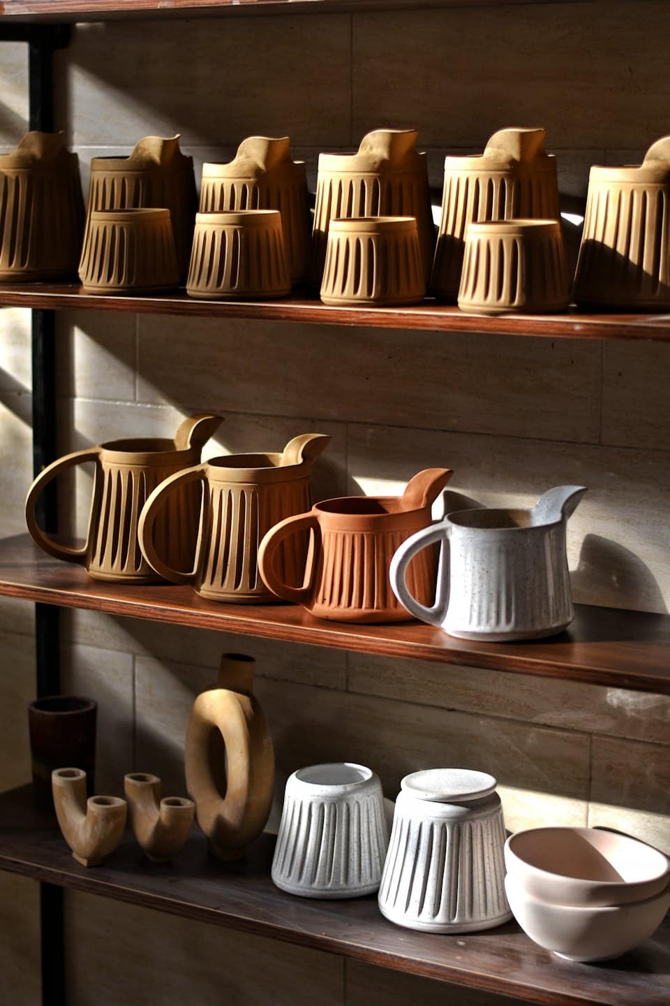 Ceramiche esposte su mensole di legno scuro.